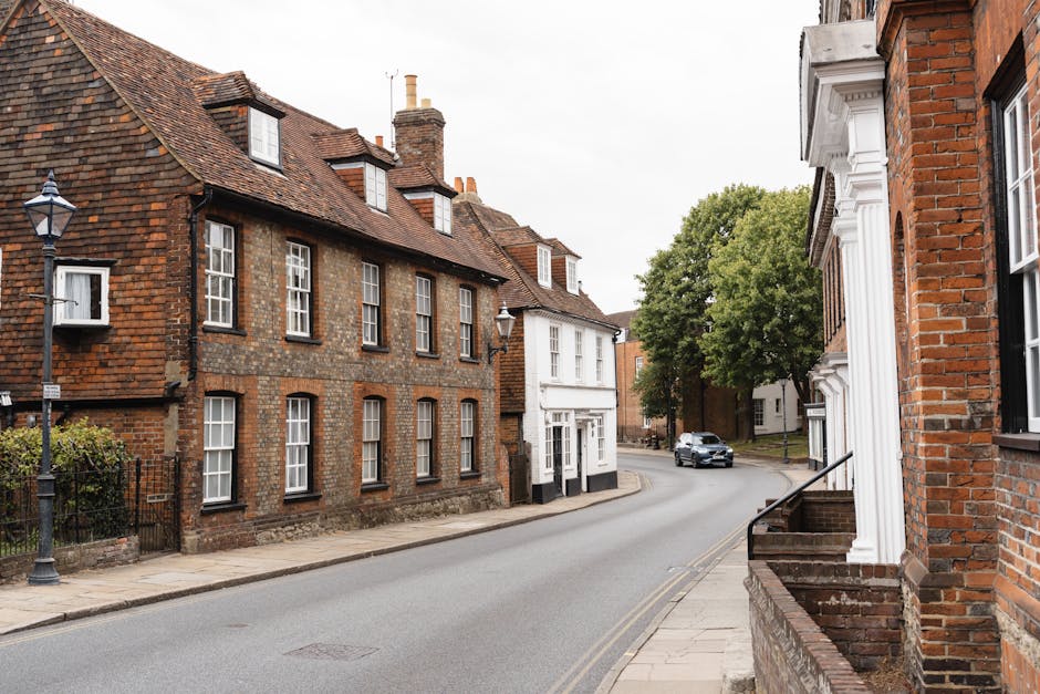 A narrow residential street in New Barnet with brick terraced houses on both sides, some with white window frames and chimneys visible on the rooftops. The street is paved with dark asphalt and featur